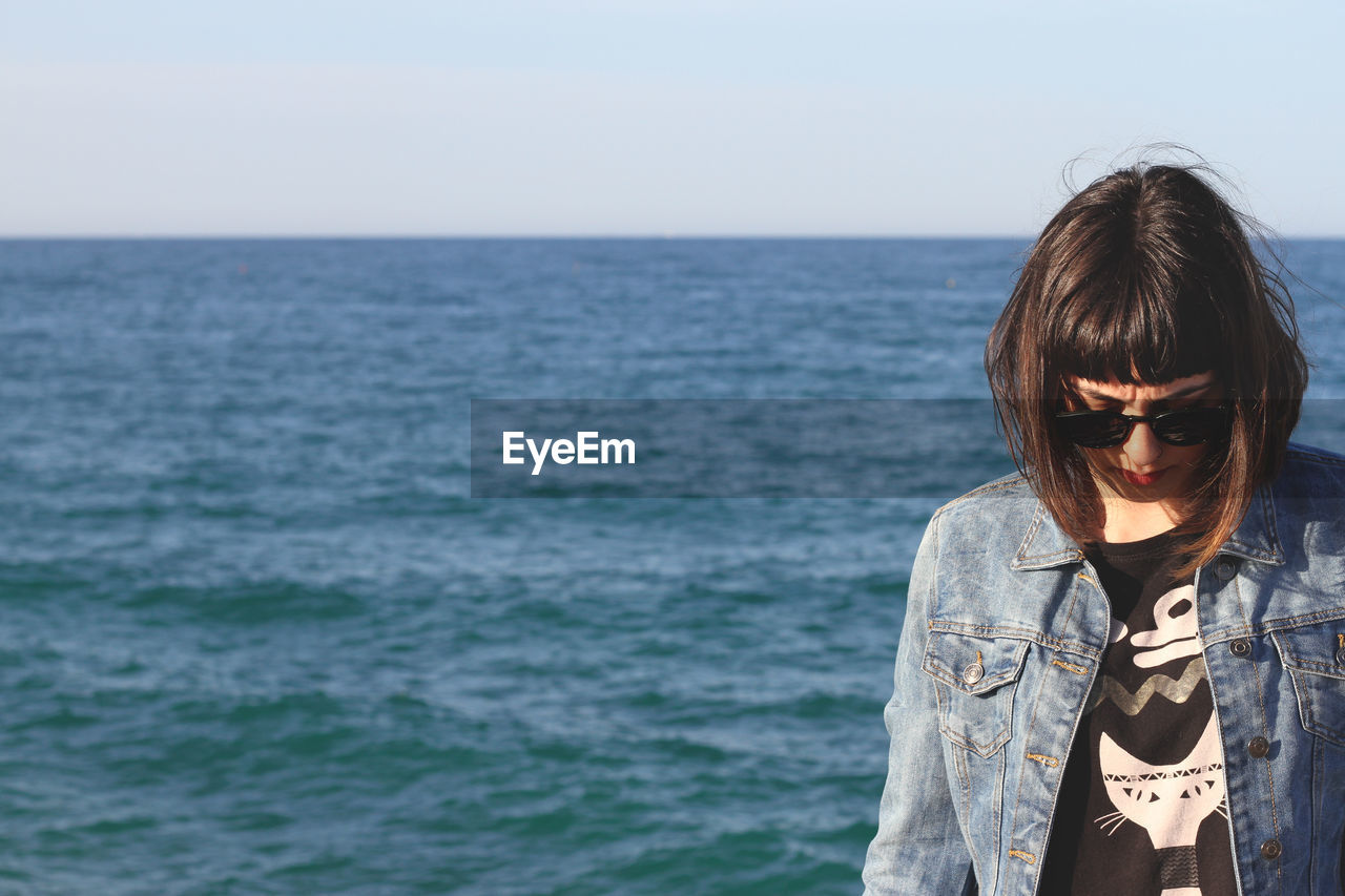 Beautiful young woman standing against sea