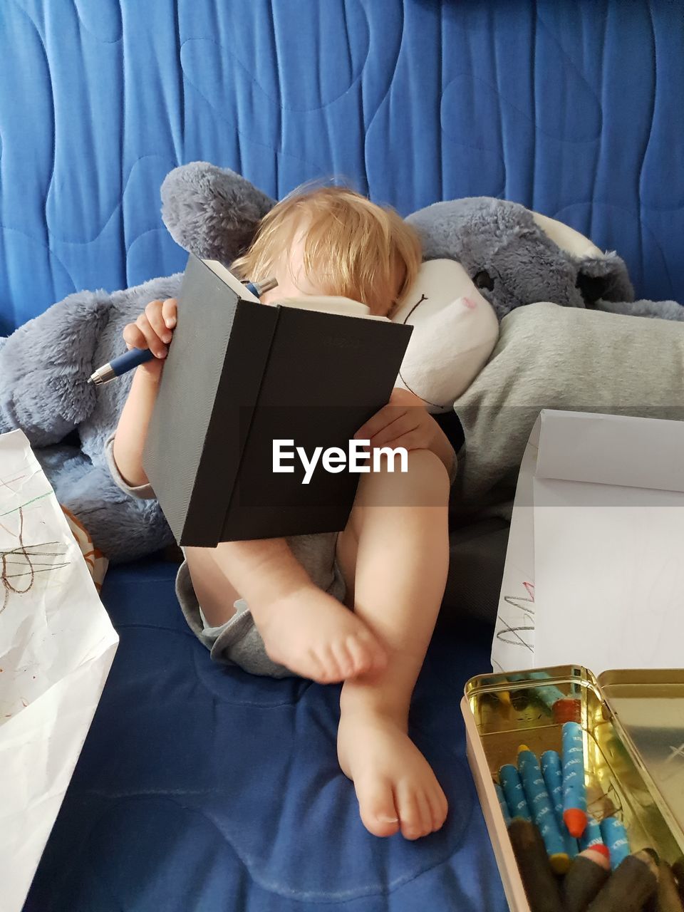 REAR VIEW OF BOY SITTING AT BOOK