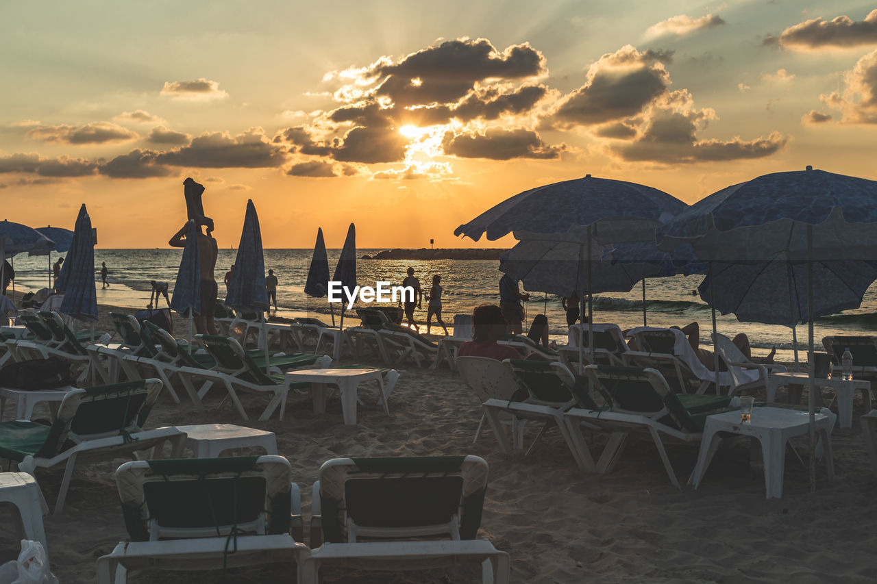 CHAIRS AND TABLES AT BEACH DURING SUNSET