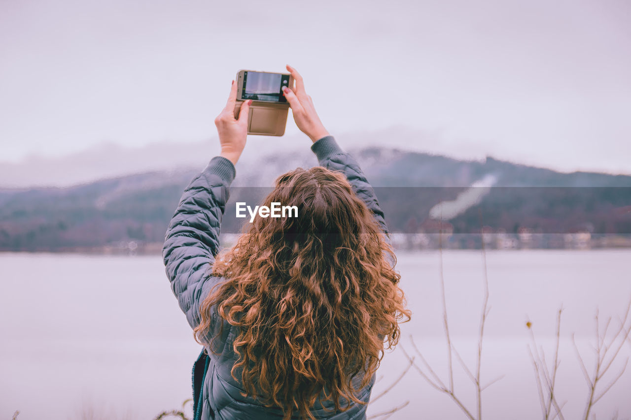 Woman photographing sky during winter