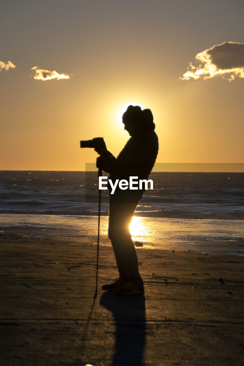 Silhouette of person standing on beach at sunset