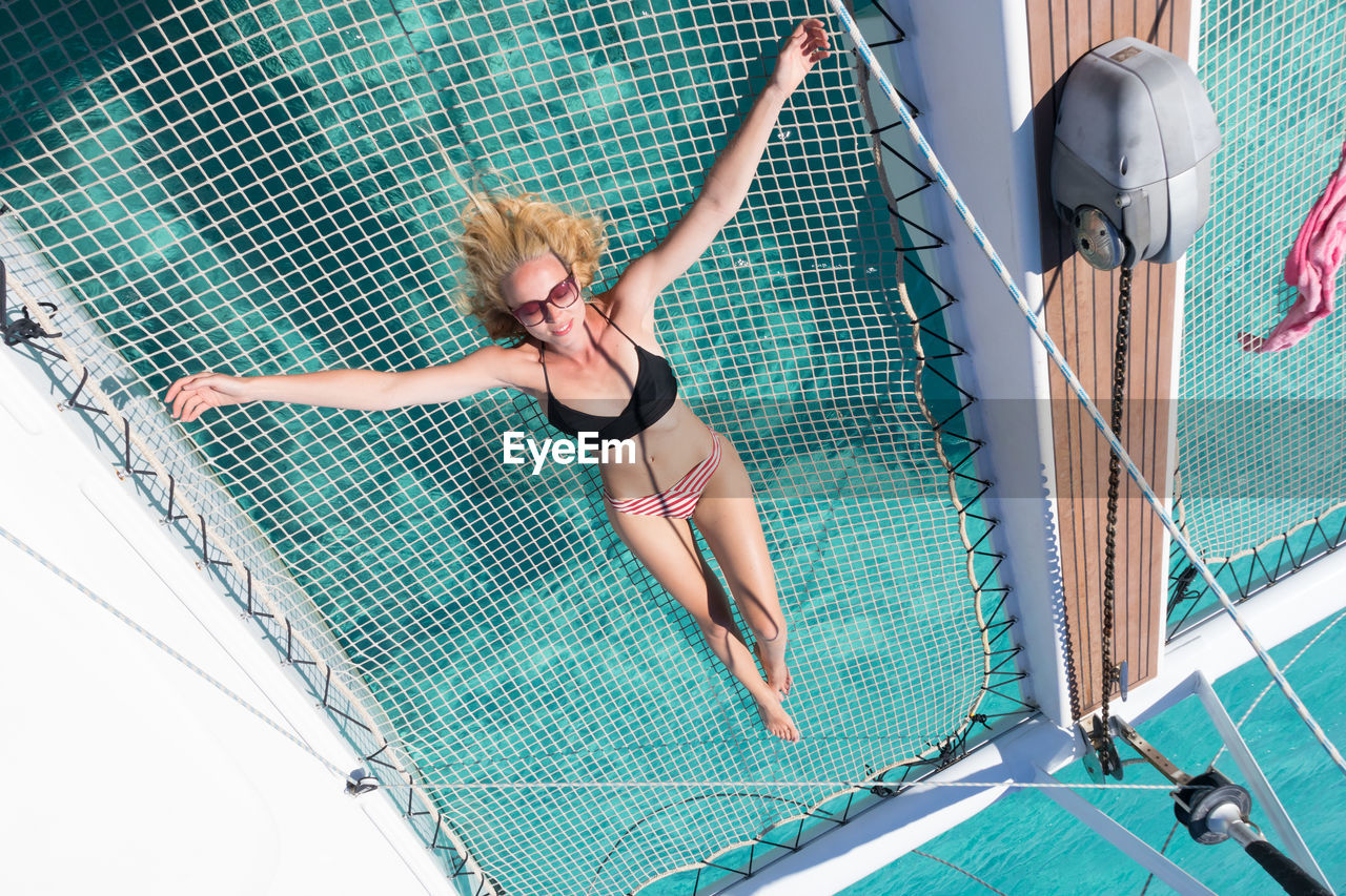 HIGH ANGLE VIEW OF WOMAN SWIMMING IN POOL