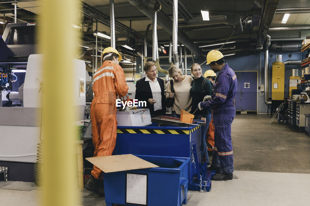 Multi-generation family discussing with male blue-collar workers working in industry