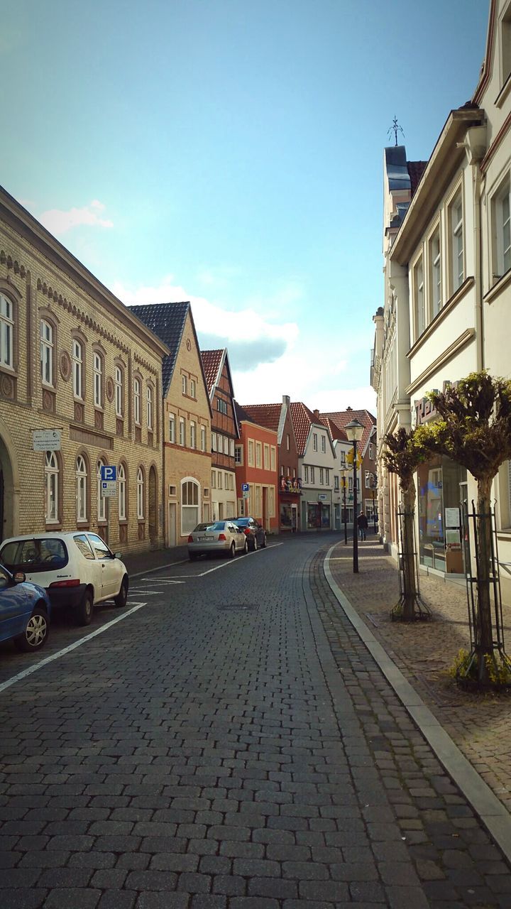 Rear view of vehicles on road along buildings