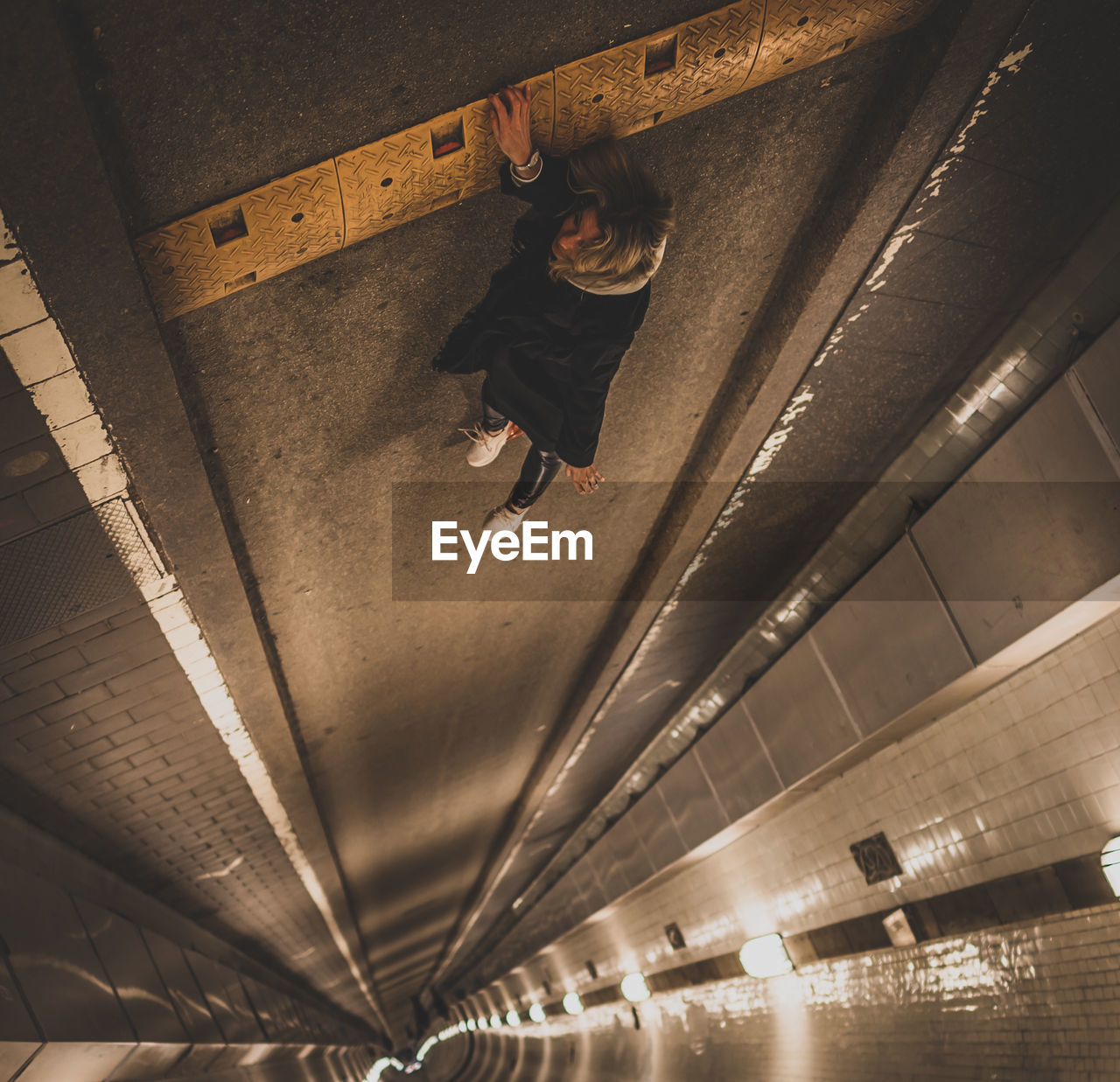 High angle view of woman lying in illuminated tunnel