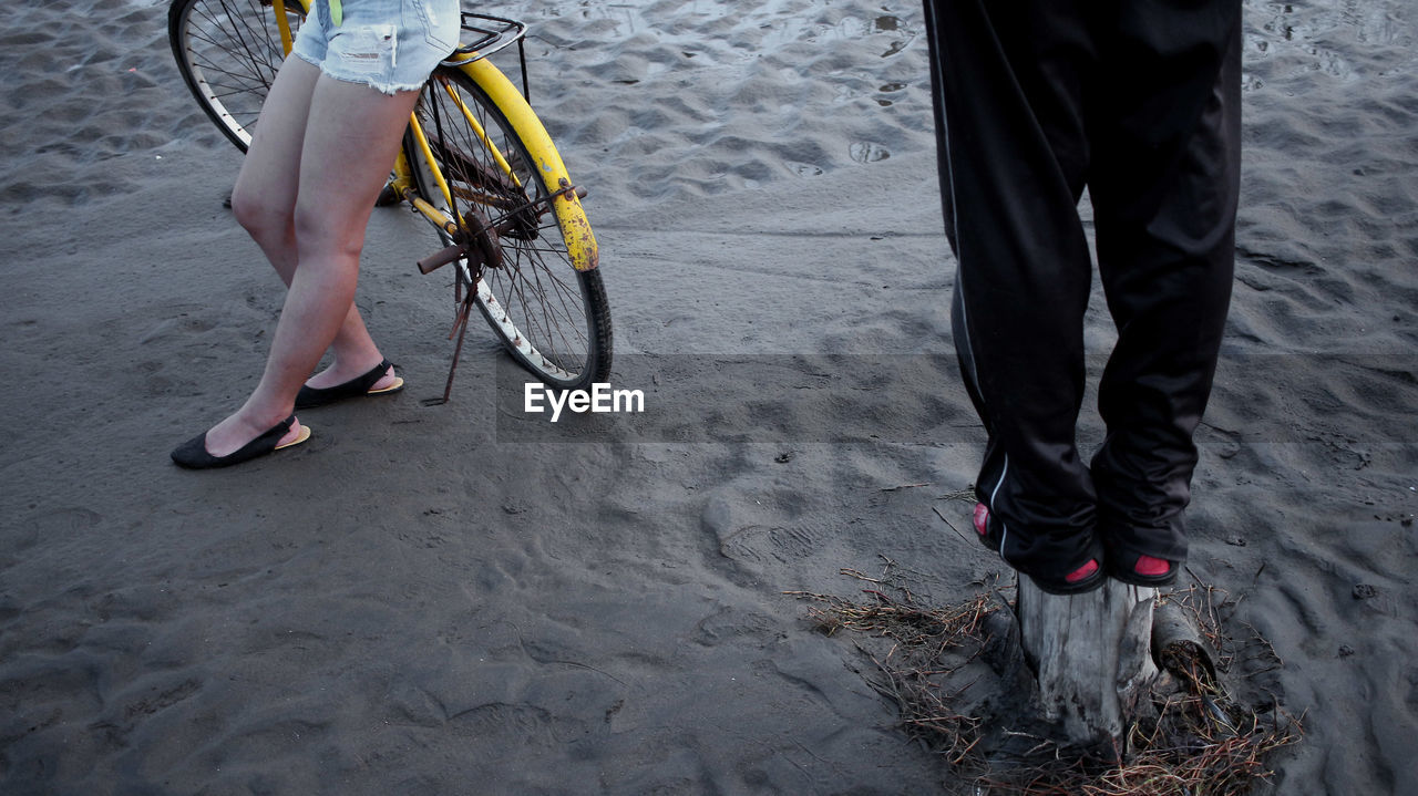 Low section of woman with bicycle on sand