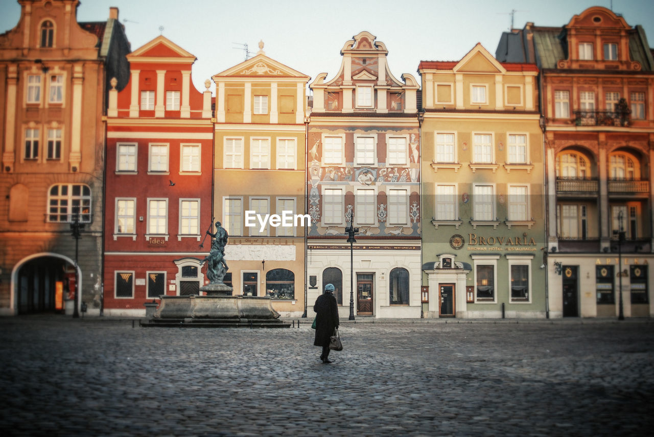 Woman walking on street against buildings