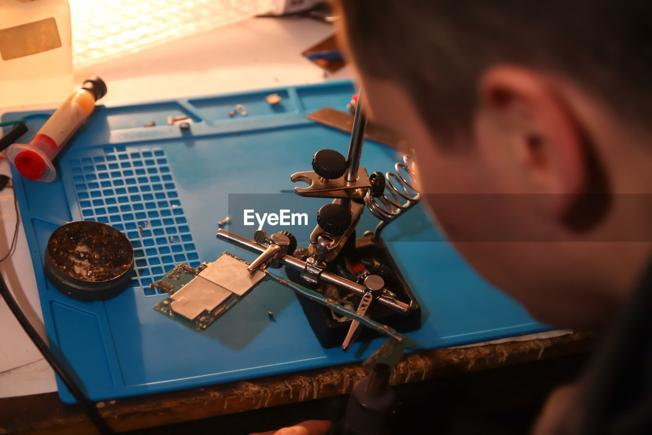 Man with microscope. work with a soldering iron. microelectronics device. close-up hands of 