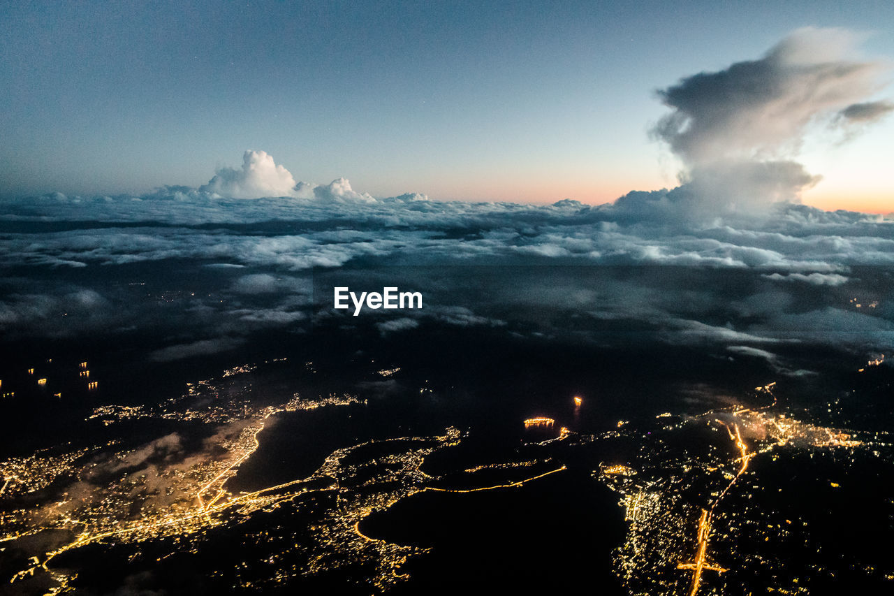 Aerial view of illuminated city against sky during sunset