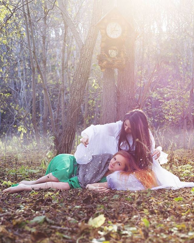 WOMAN SITTING ON TREE TRUNK IN FOREST