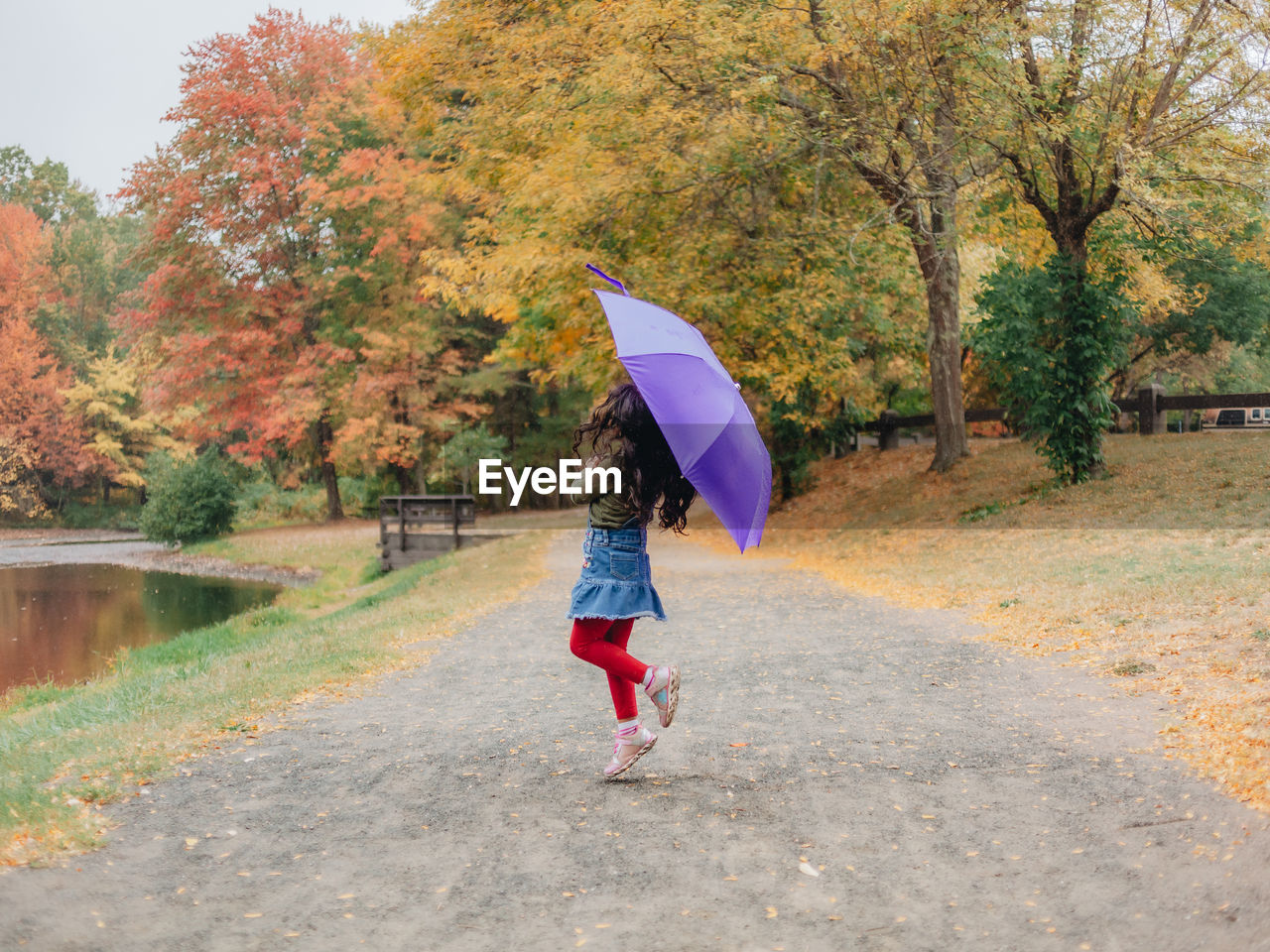 Full length of girl holding umbrella standing at park