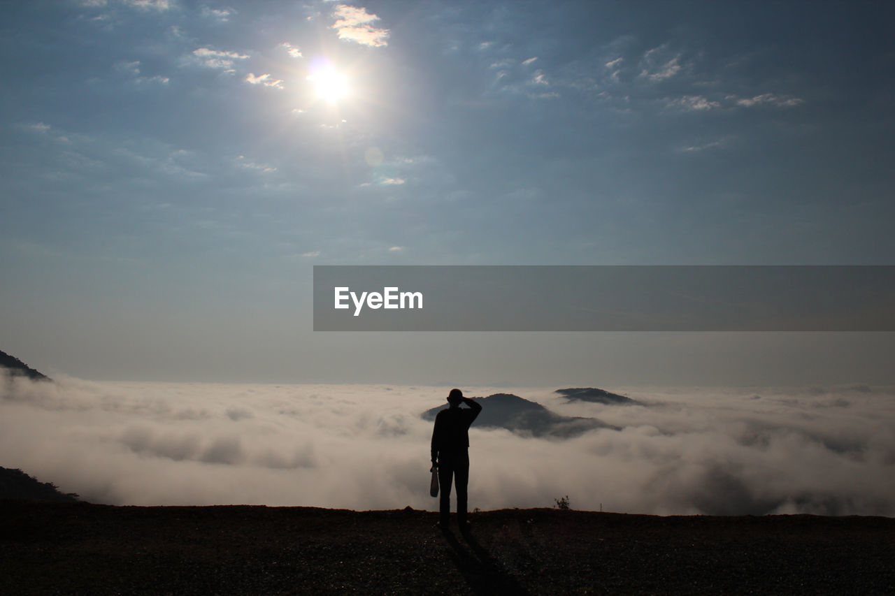 Rear view of man standing against cloudscape