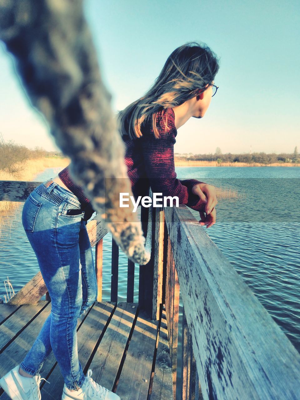 Side view of woman leaning on railing by sea