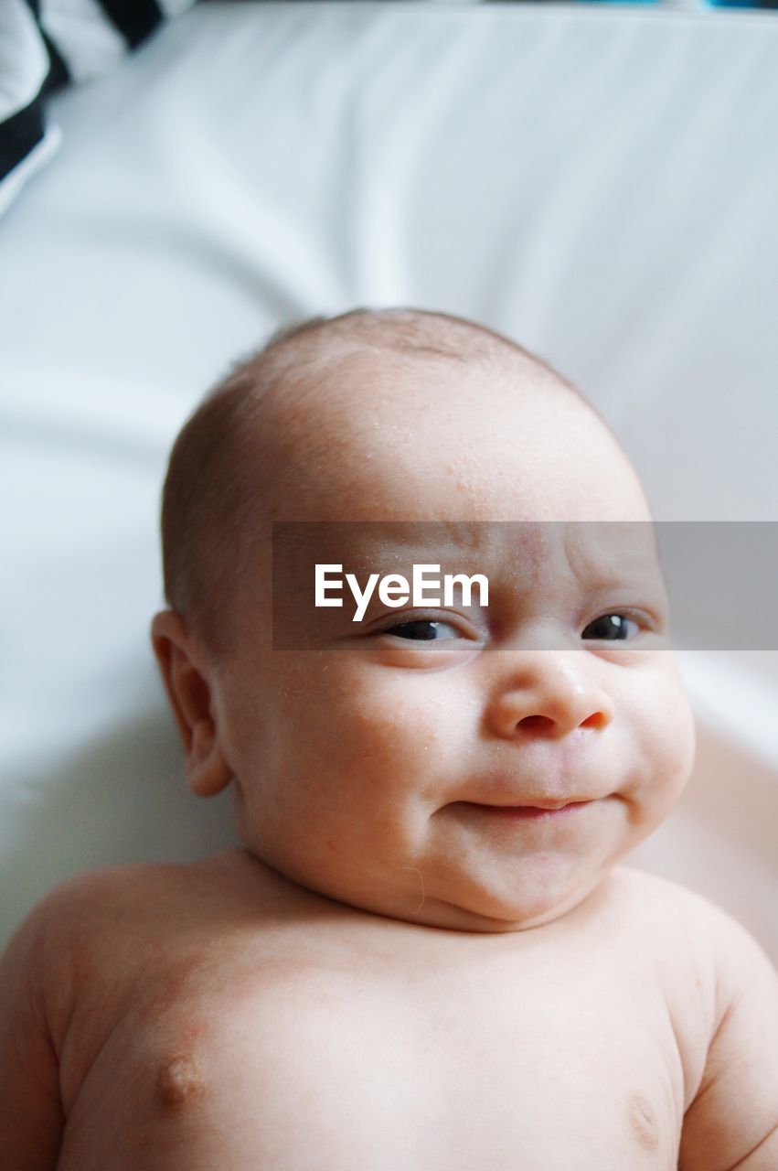 Close-up of portrait of baby boy lying on bed