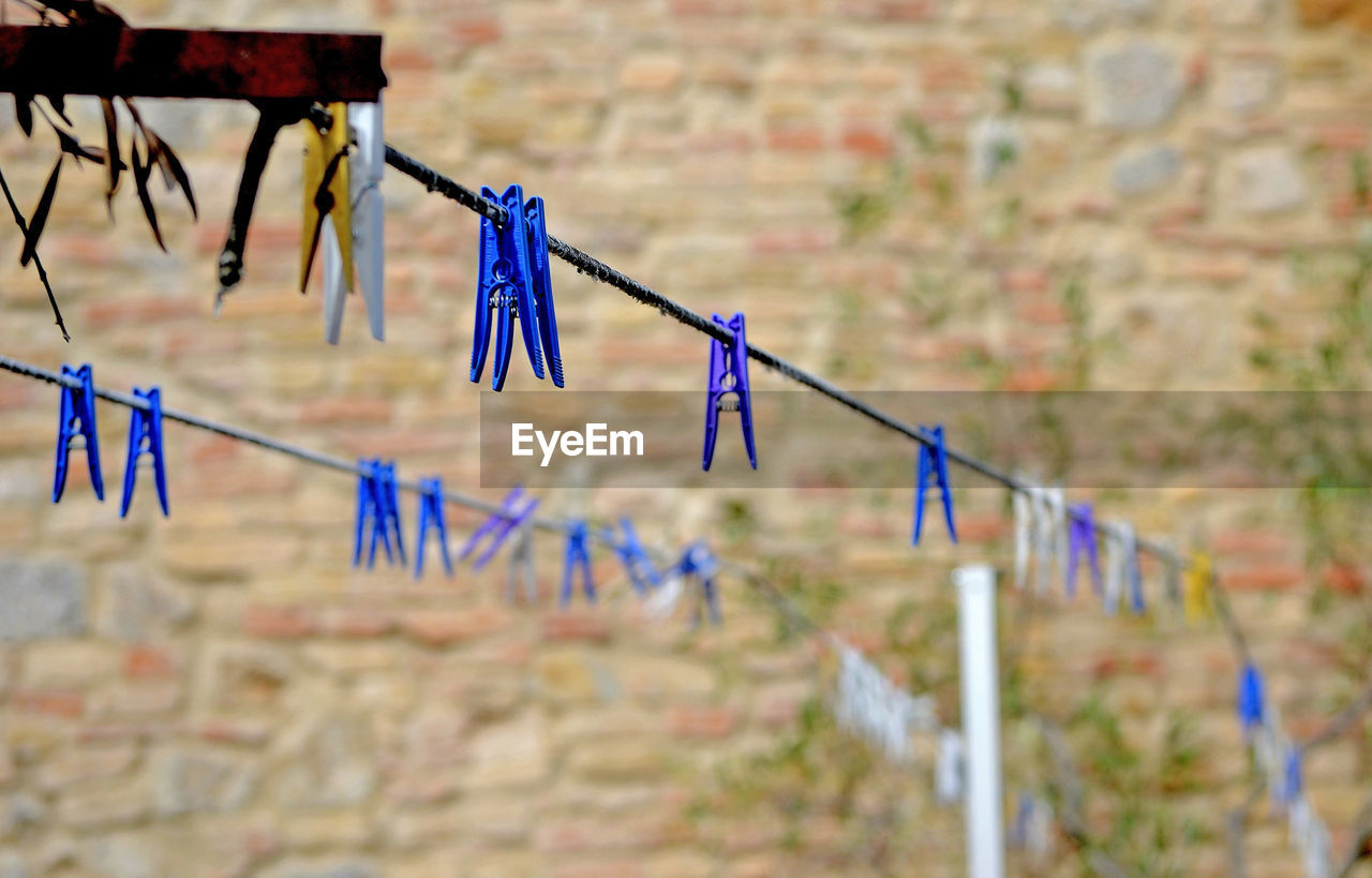 Multi colored clothespins hanging on rope against fence