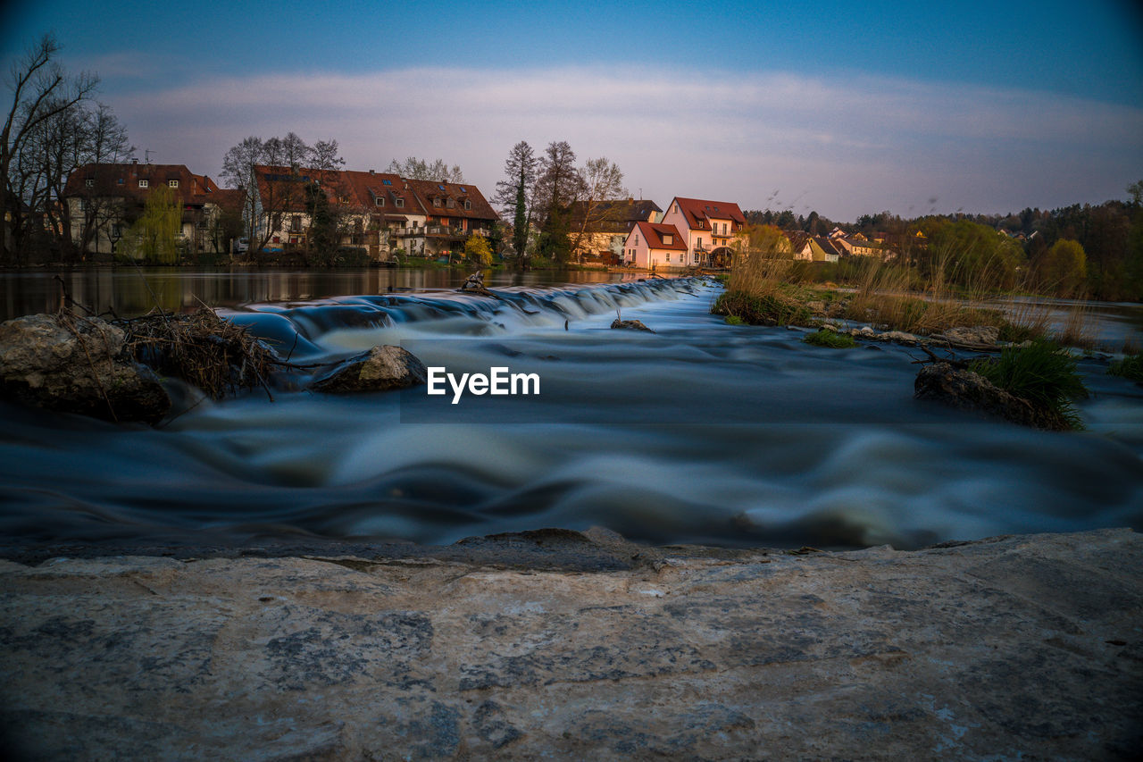 River flowing amidst buildings against sky