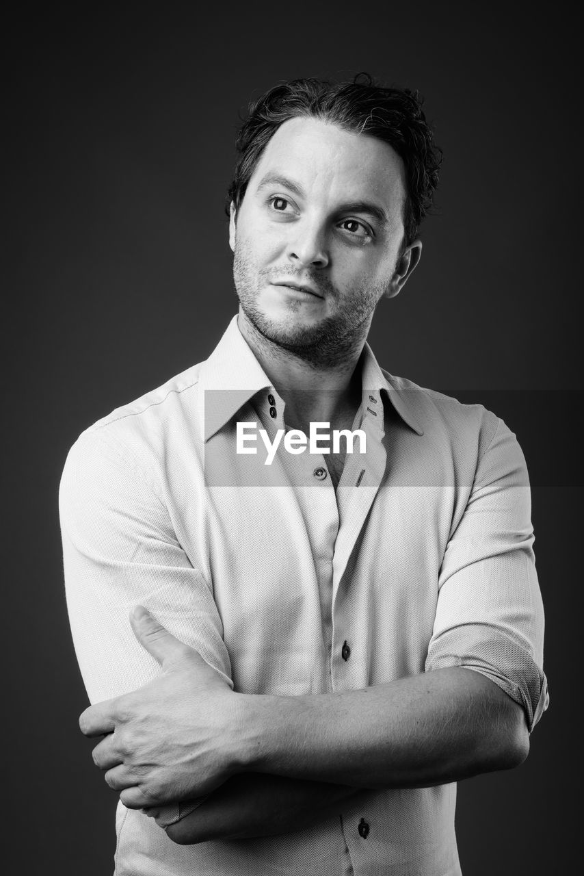 Man looking away while standing against black background