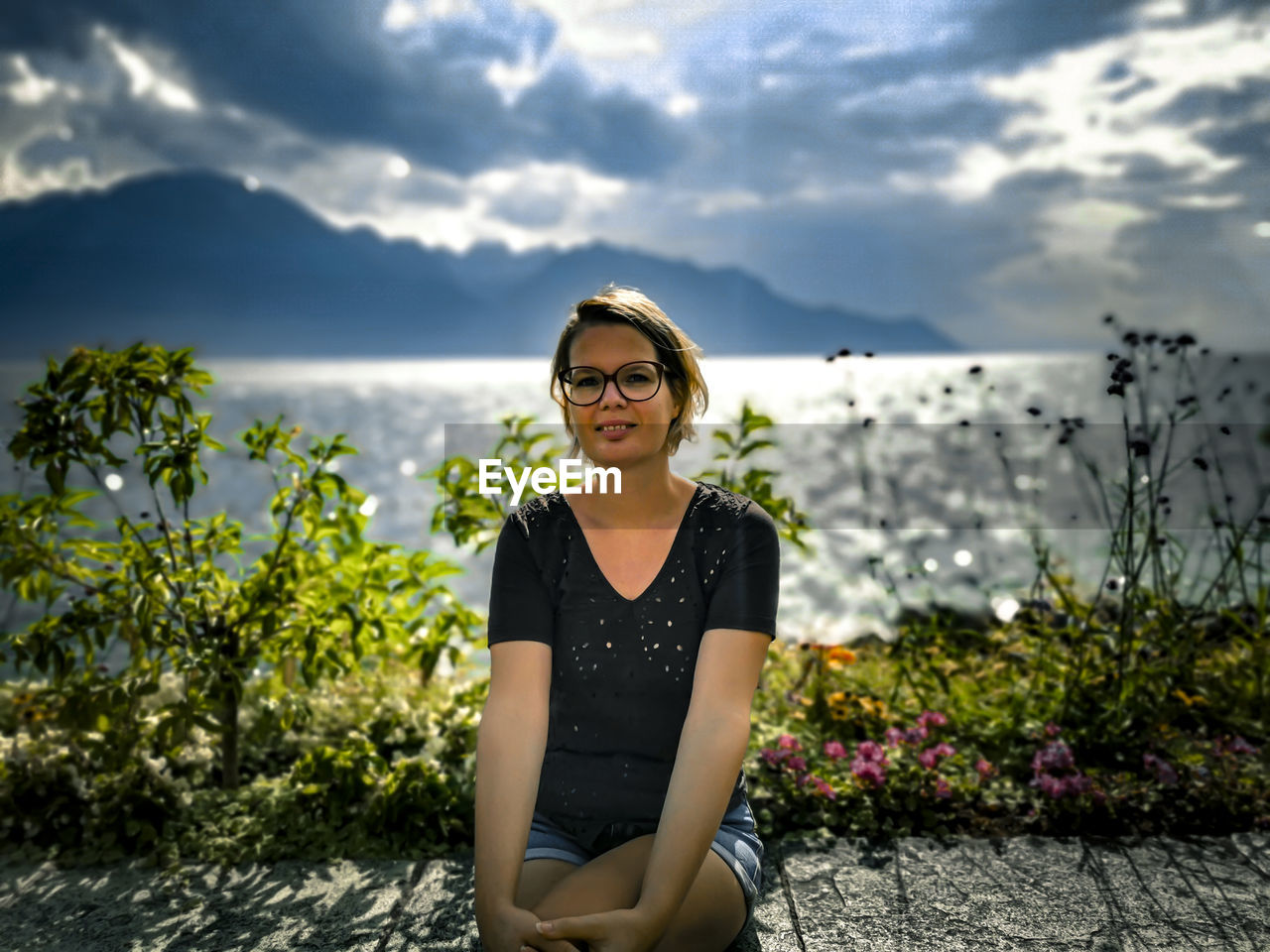 Portrait of young woman standing against sky