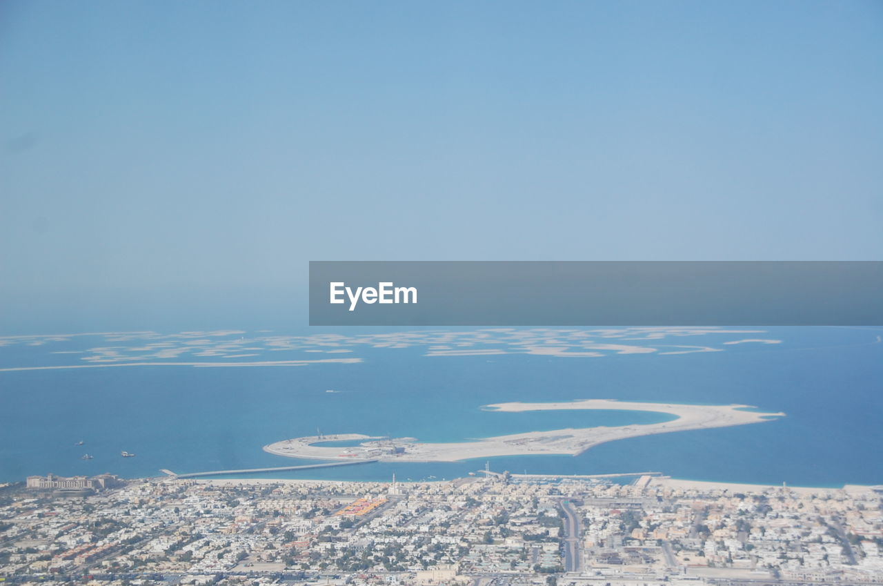 Aerial view of city by sea against clear sky