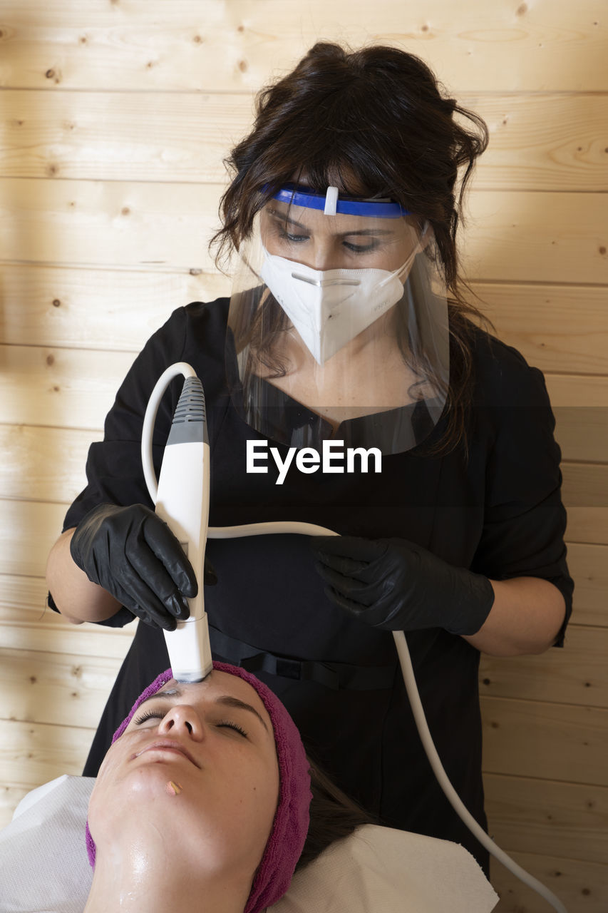 Beautician working with mask and protective screen for the virus covid