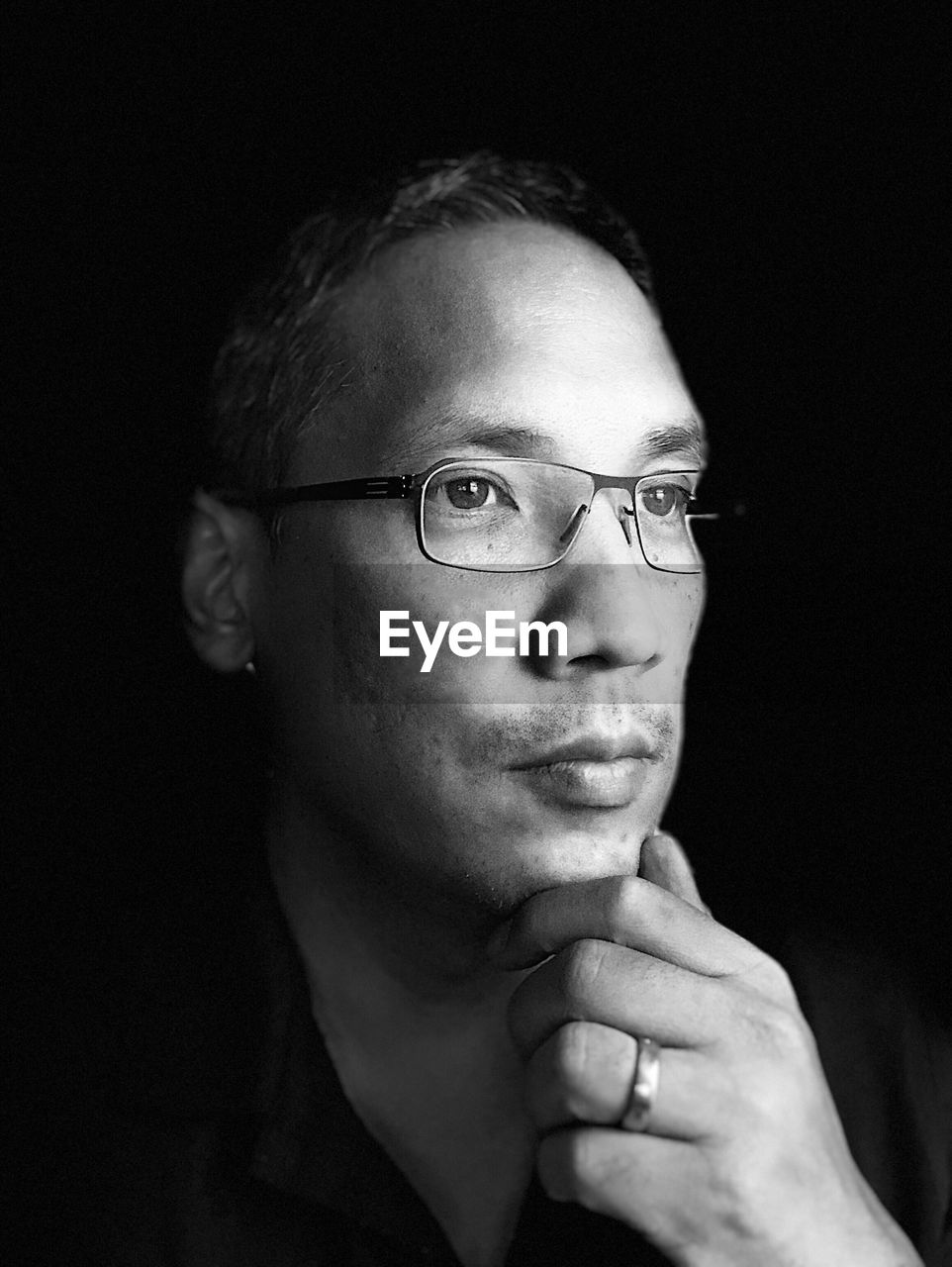 Thoughtful man wearing eyeglasses against black background