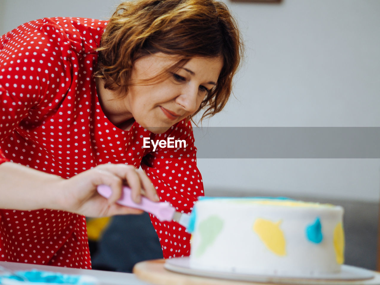 Mature woman cutting cake at home