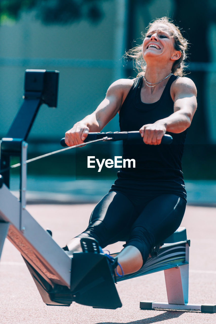 Woman exercising in gym during sunny day