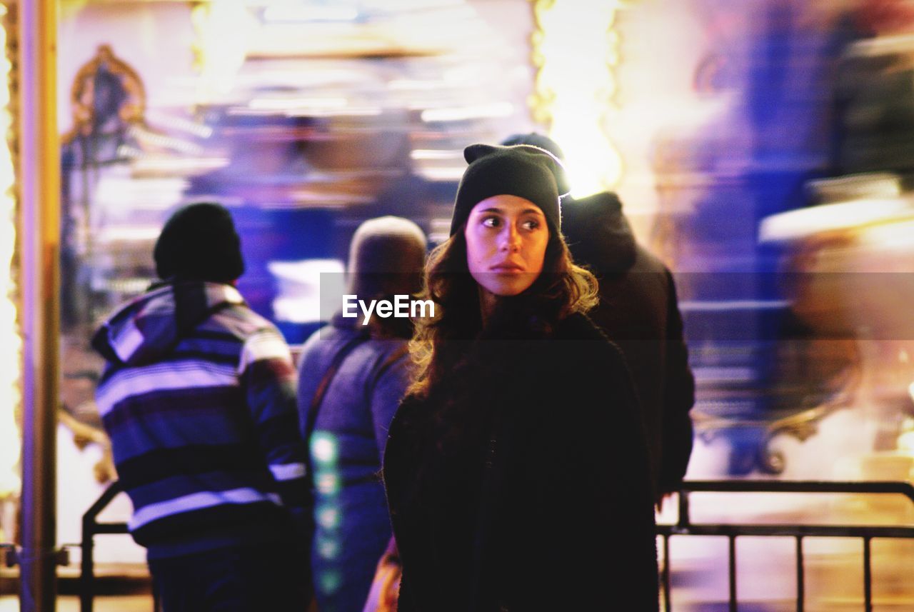 PORTRAIT OF PEOPLE STANDING IN ILLUMINATED CITY
