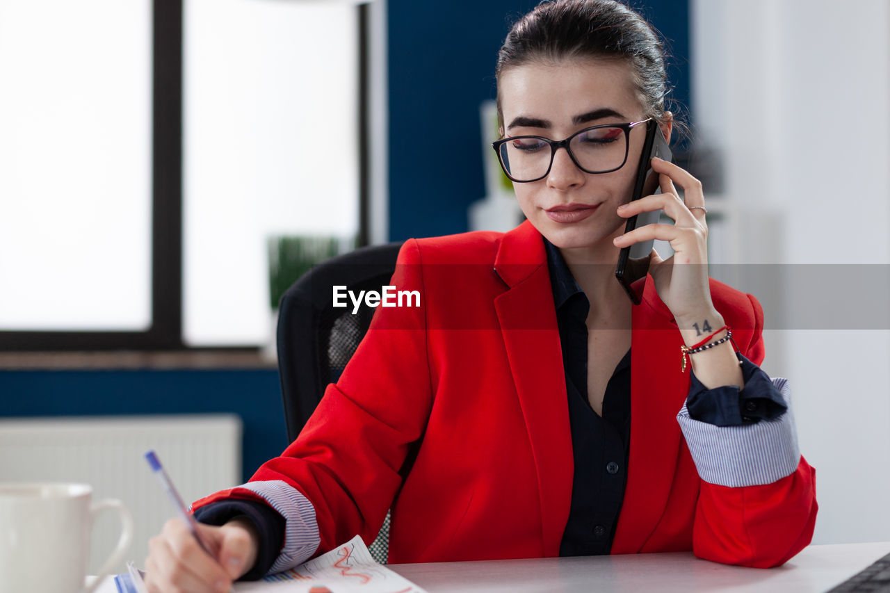 Businesswoman talking on phone while working at office