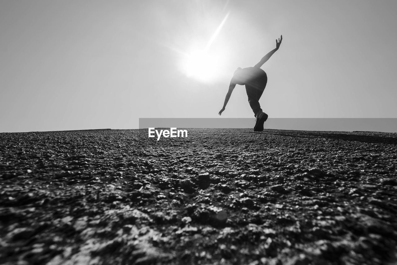 FULL LENGTH OF YOUNG WOMAN JUMPING IN MID-AIR