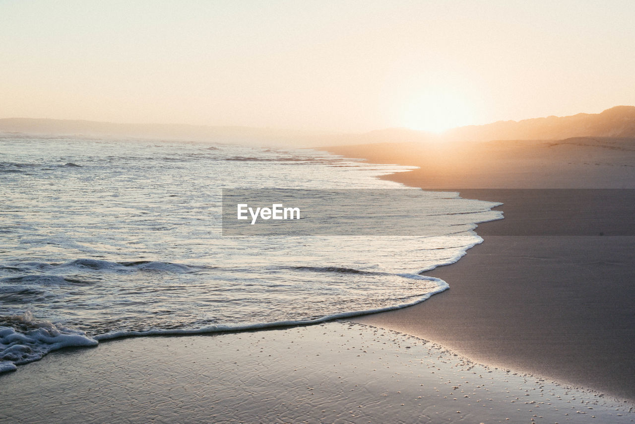 Scenic view of beach against clear sky during sunset