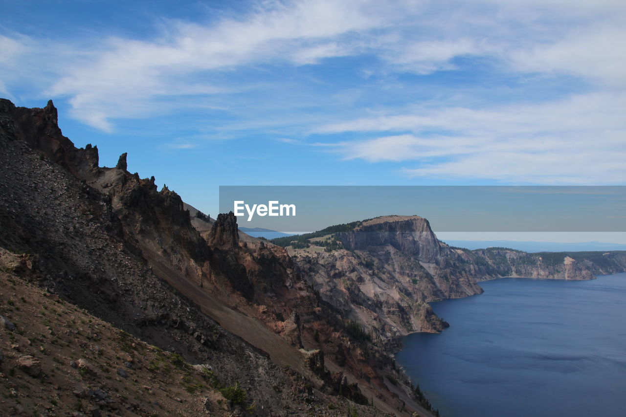 Scenic view of cliff by crater lake against sky