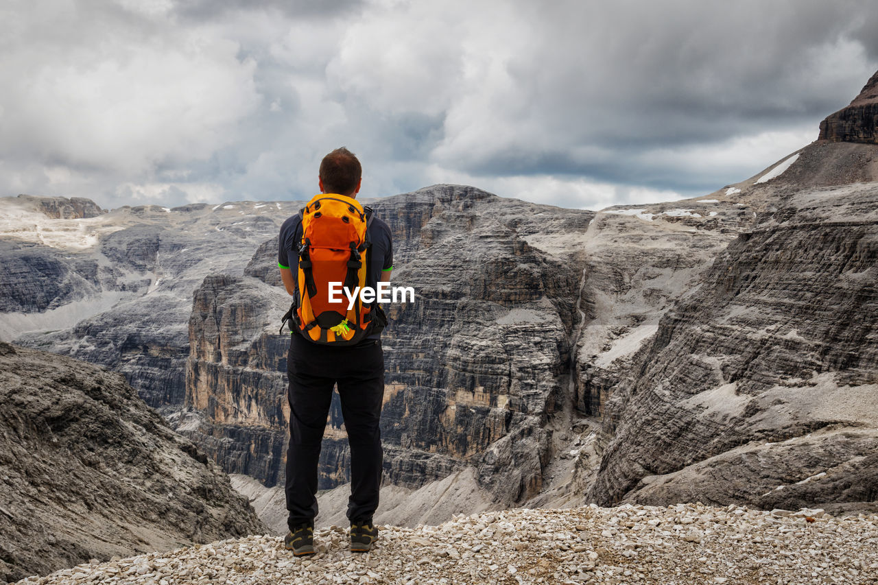 Rear view of hiker standing against dolomites