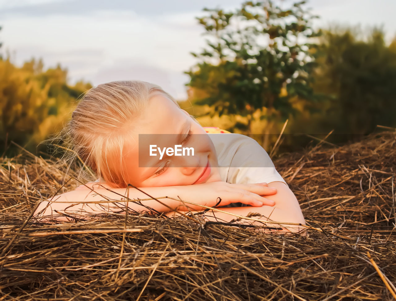 child, one person, baby, childhood, lying down, nature, blond hair, relaxation, plant, toddler, eyes closed, innocence, grass, portrait, portrait photography, cute, autumn, emotion, smiling, day, happiness, outdoors, person, sunlight, summer, headshot, lifestyles, land, sky, sleeping, straw, leisure activity, tranquility, lying on front, resting, men, casual clothing, field