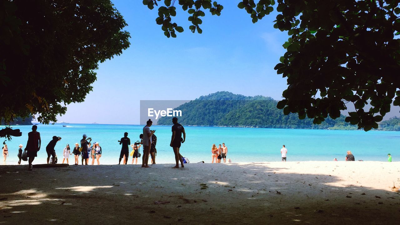 PEOPLE AT BEACH AGAINST SKY