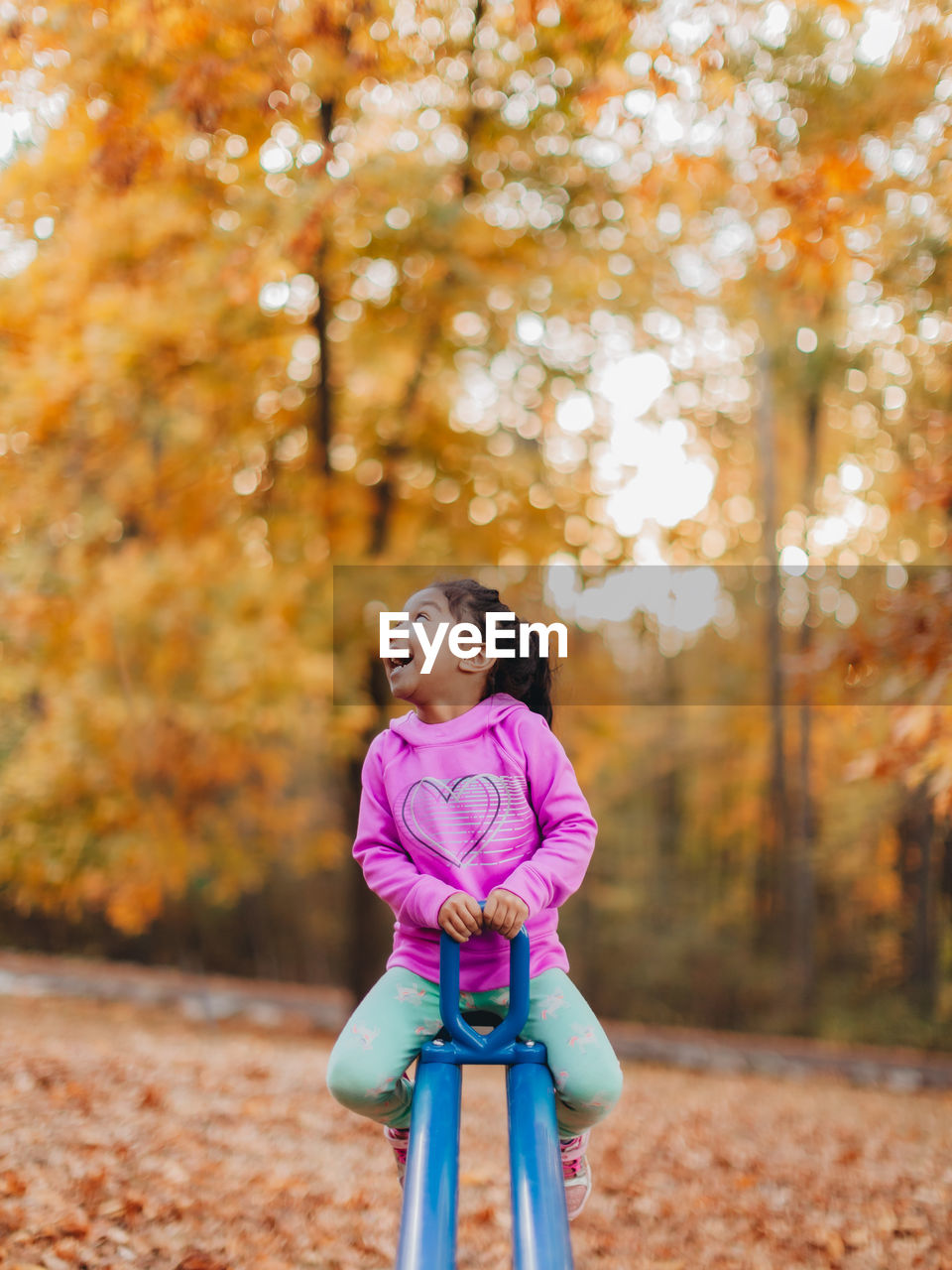 Girl looking away while playing at playground during autumn