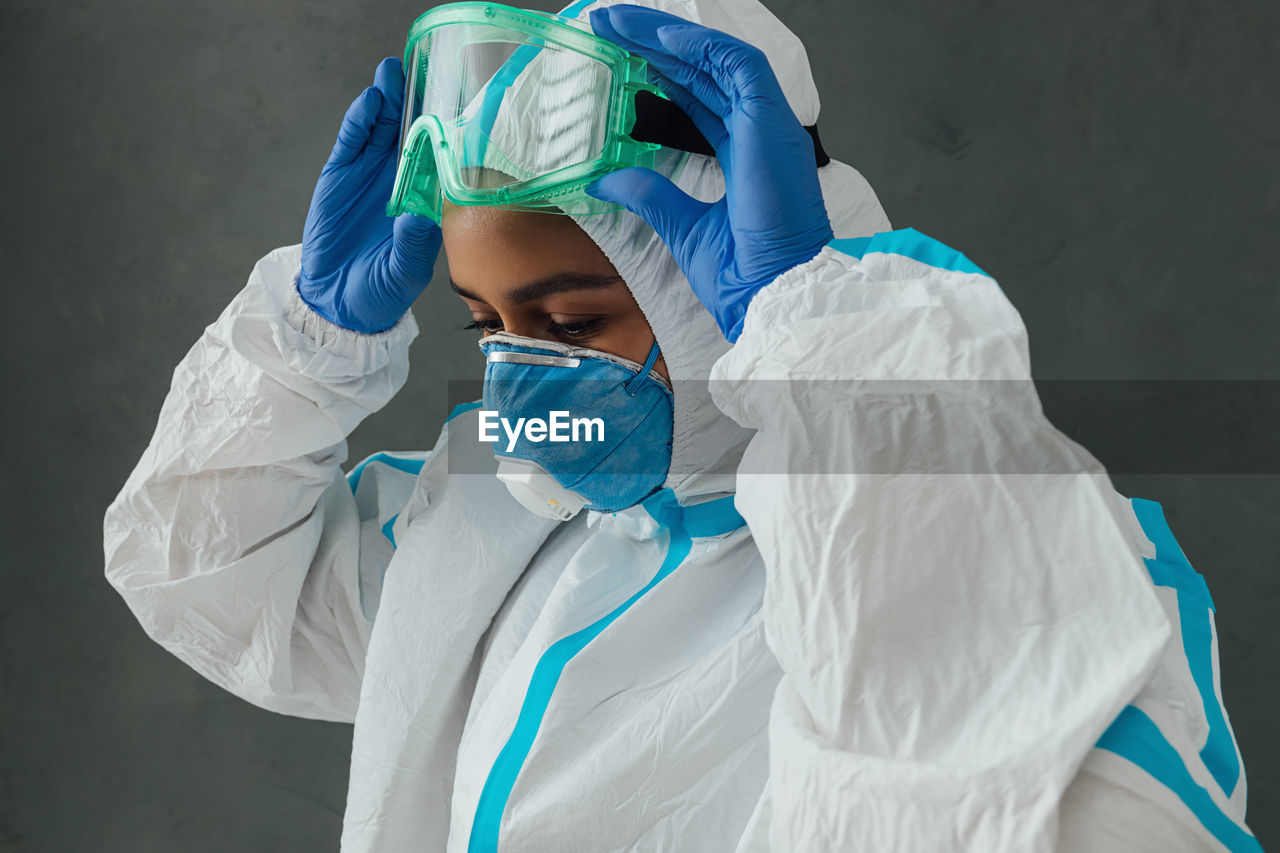 Close-up of young woman wearing protective suit against wall