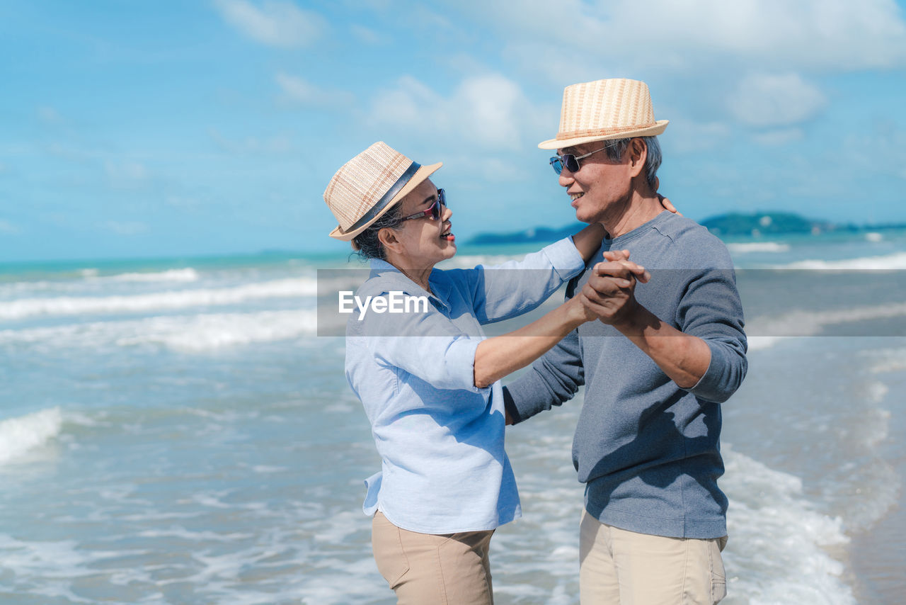 Happy couple dancing while standing at beach