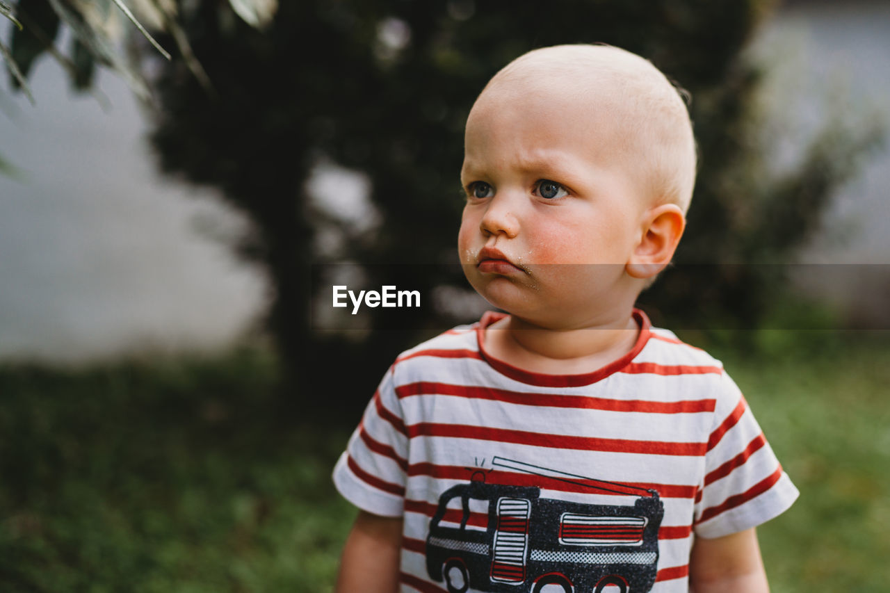 Portrait of beautiful boy with serious face looking to side outside