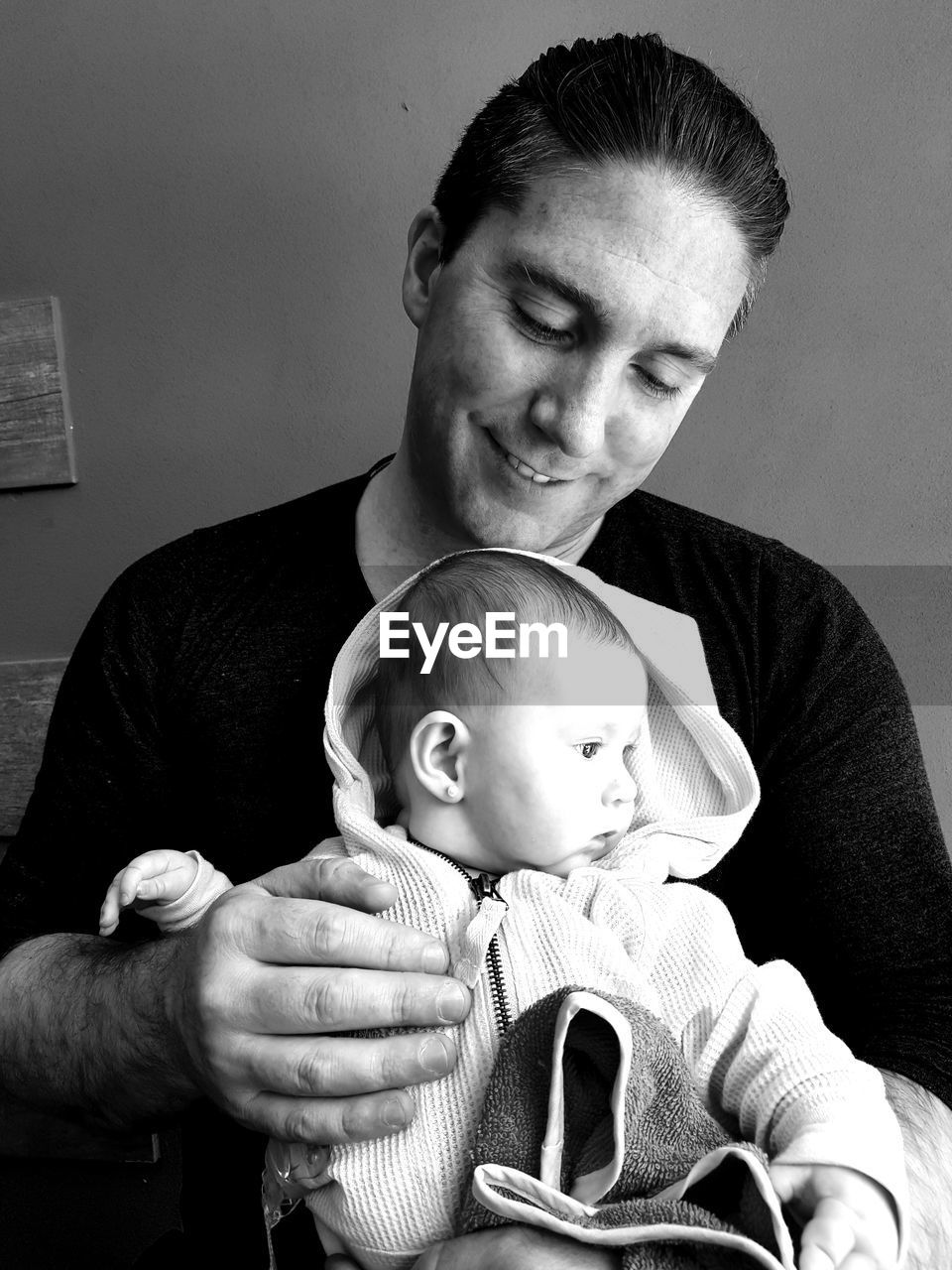 Father looking at daughter while sitting against wall at home