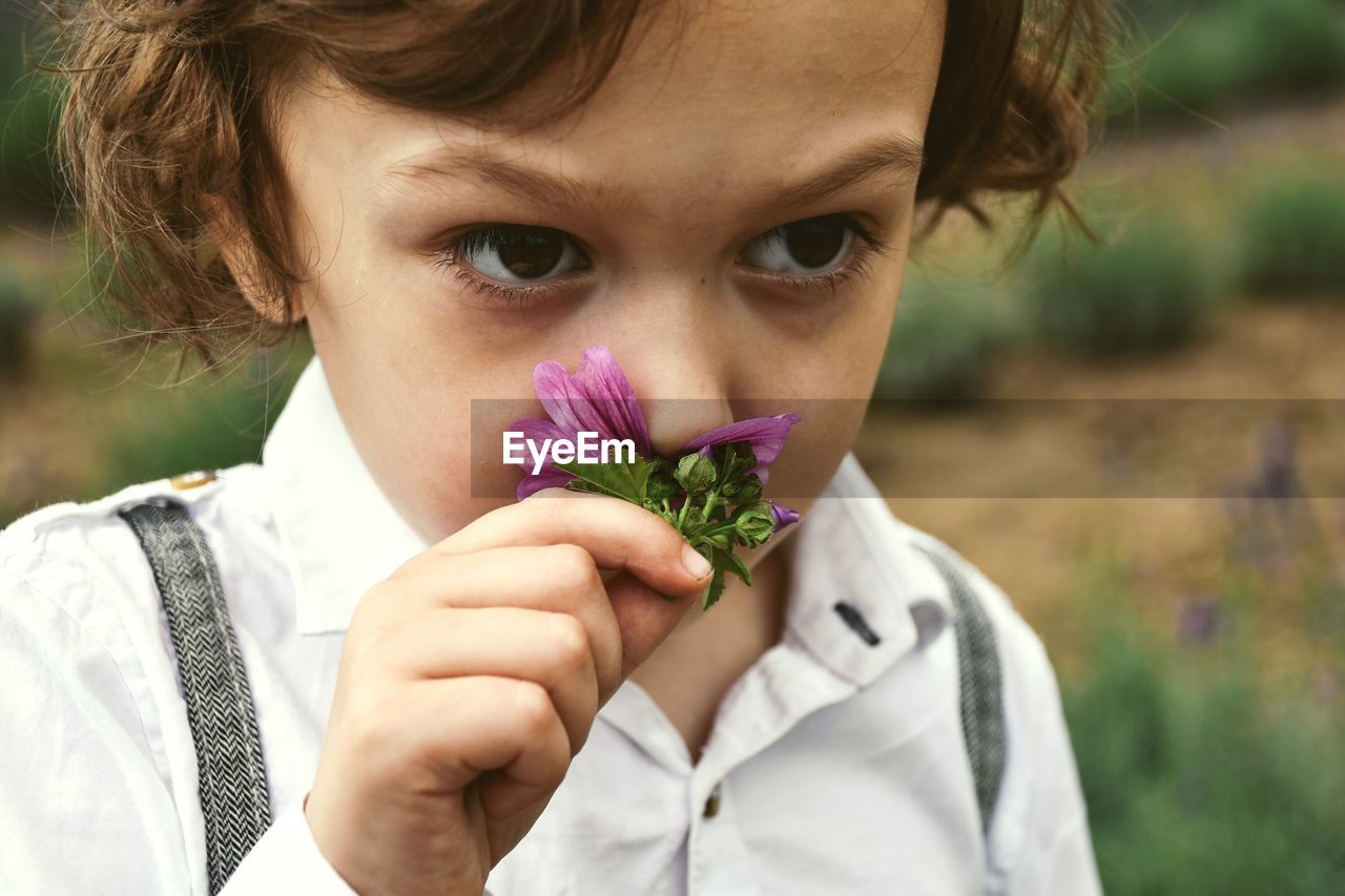 Close-up of boy smelling flower