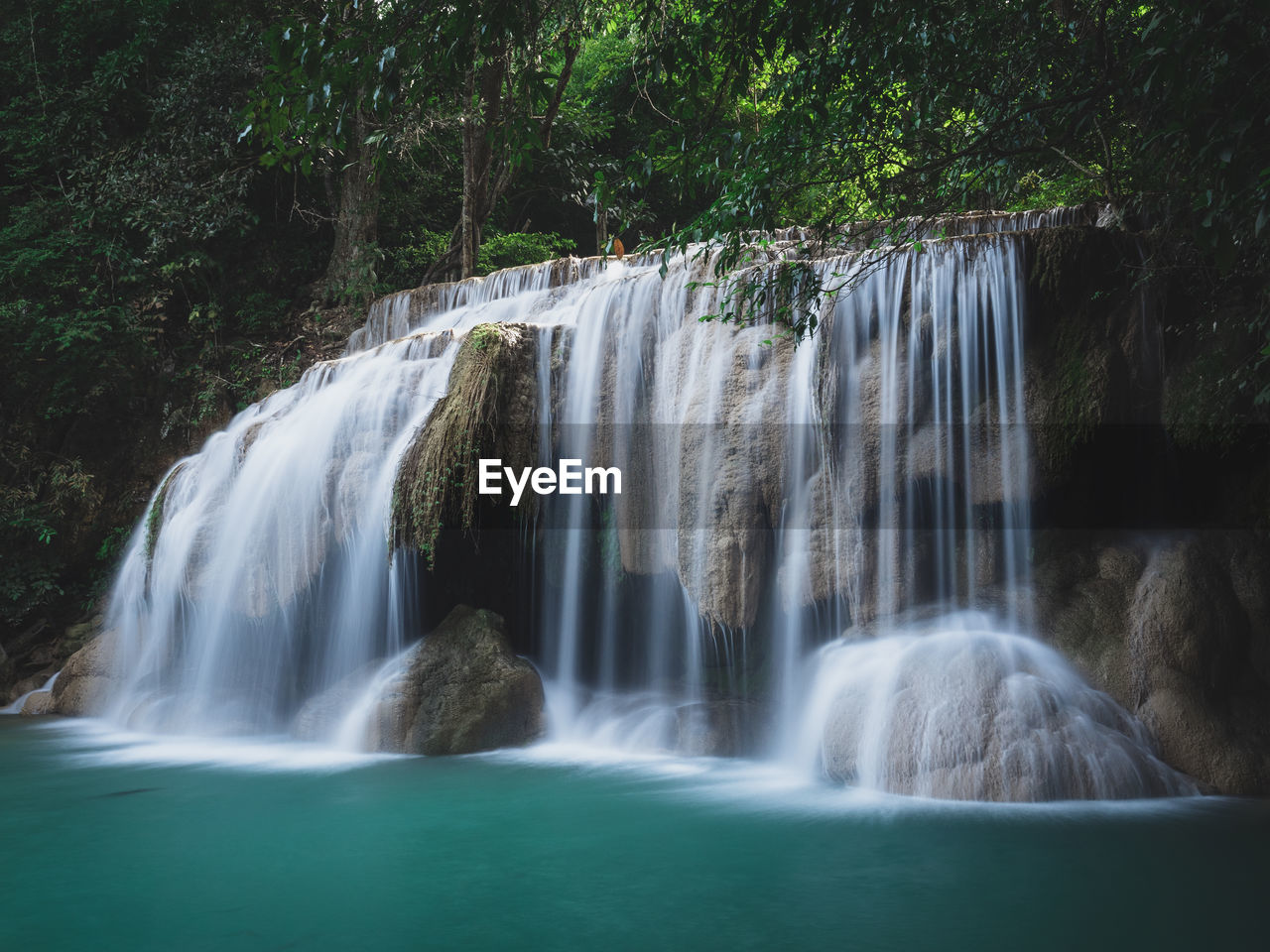 Scenic paradise waterfall with turquoise pond in rainforest. erawan falls, kanchanaburi, thailand.