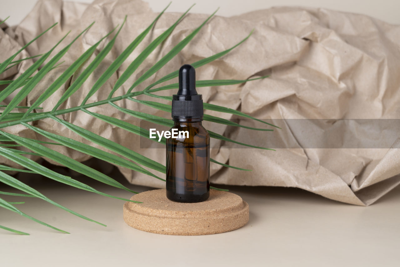 Cbd face serum or oil in brown dropper bottle with green leaf beside it on a craft paper background