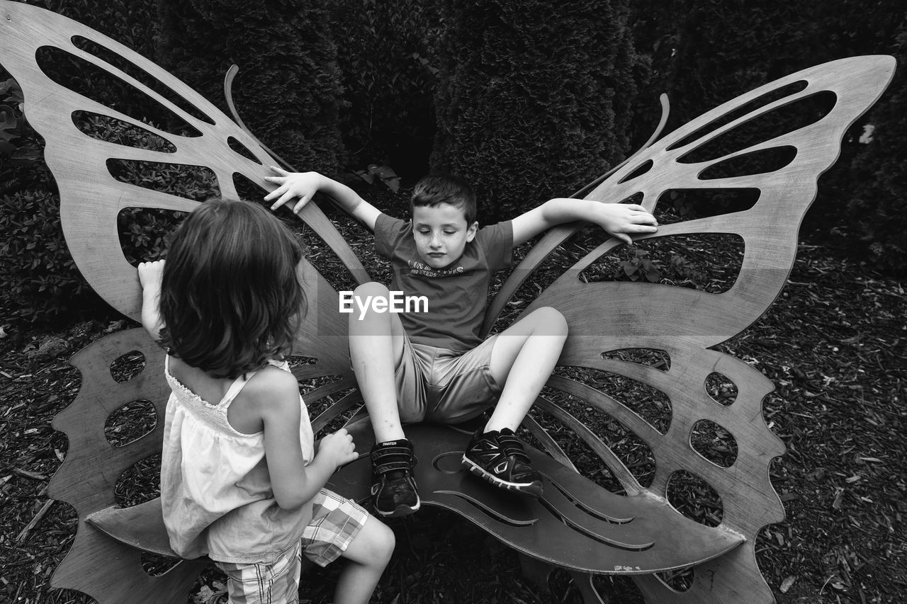 Siblings playing with wing shaped chair
