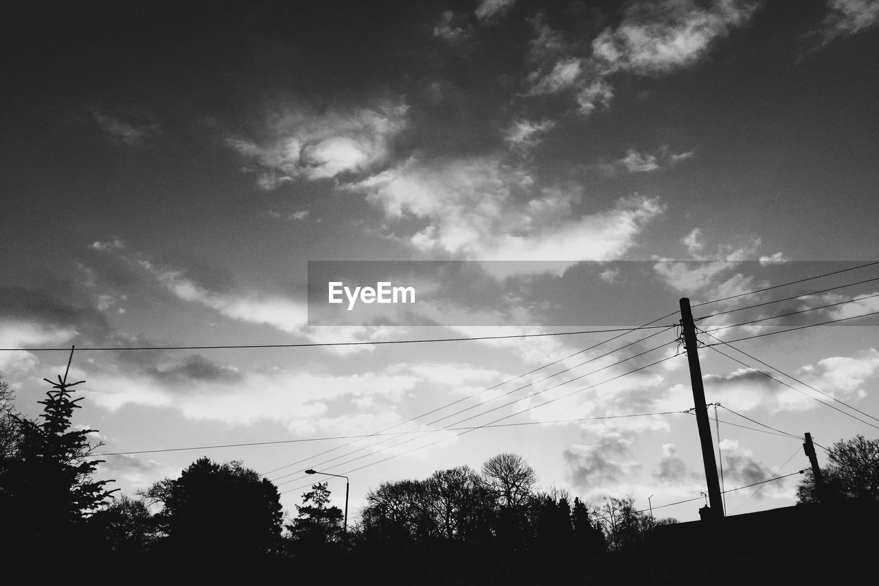 Low angle view of electricity pylon against cloudy sky