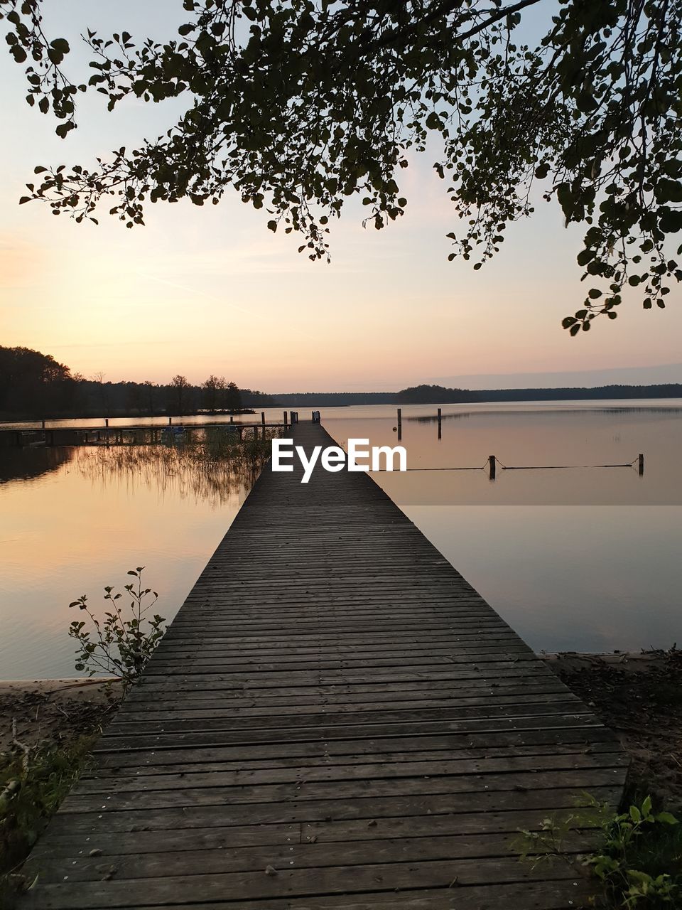 Pier over lake against sky during sunset