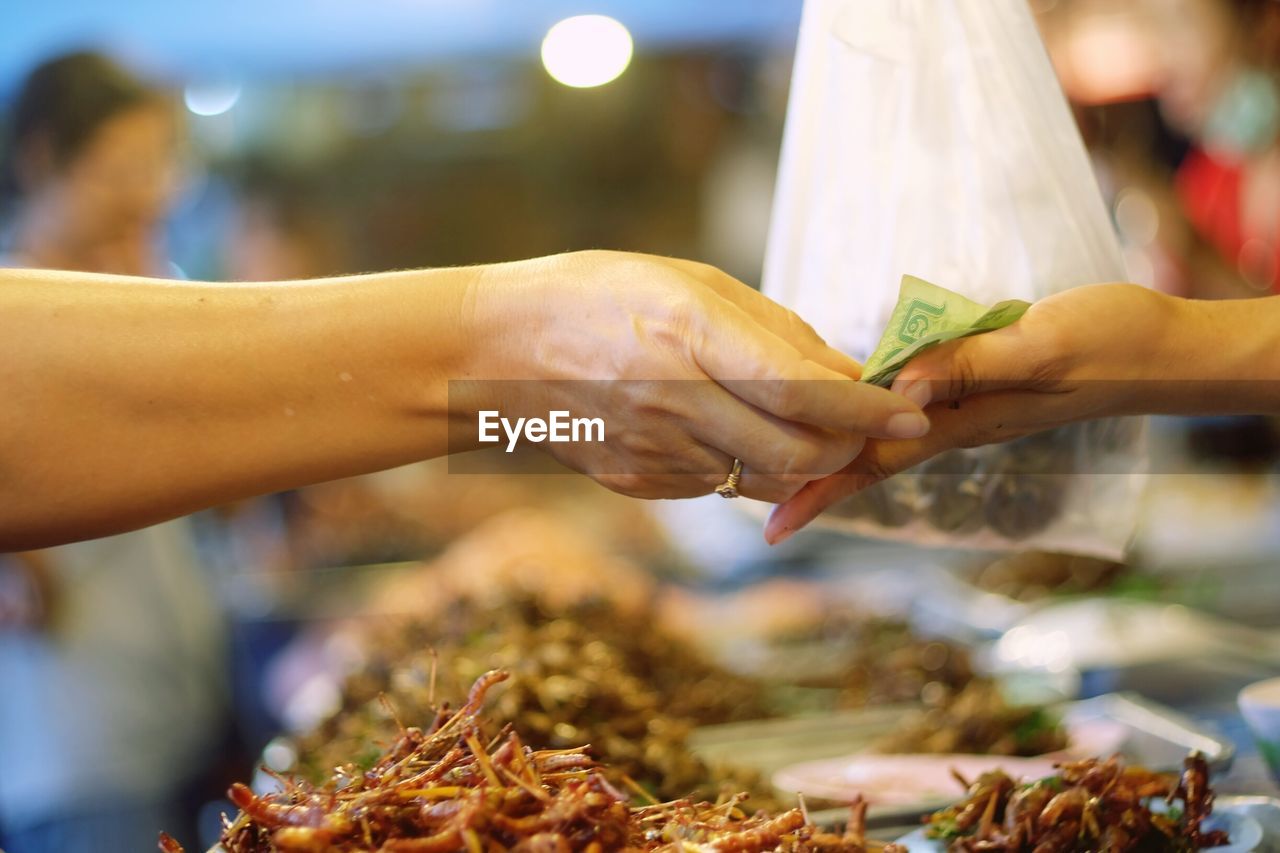 Cropped hand of woman giving money to person at market