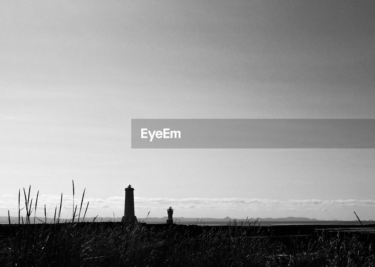 Lighthouse on field against clear sky