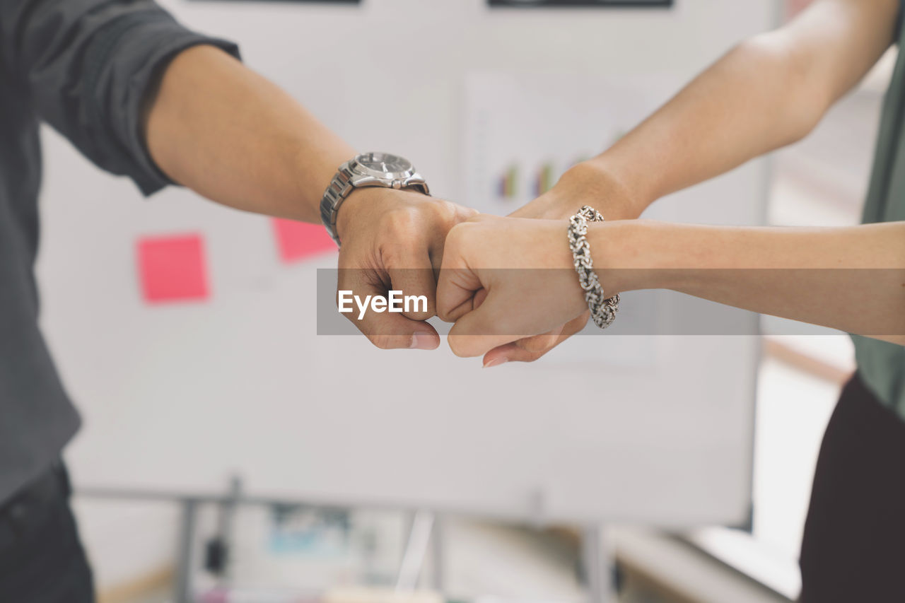 Colleagues giving fist bumps in office