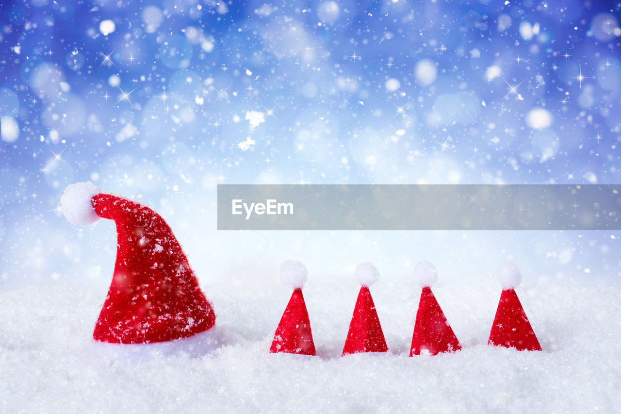 Close-up of santa hats on snow during during snowfall